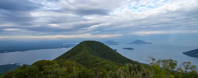 A forested ridge above the Gulf of Fonseca, with islands beneath a cloudy sky.