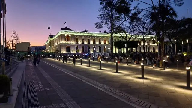 The illuminated Palacio Nacional and plaza in San Salvador at dusk.